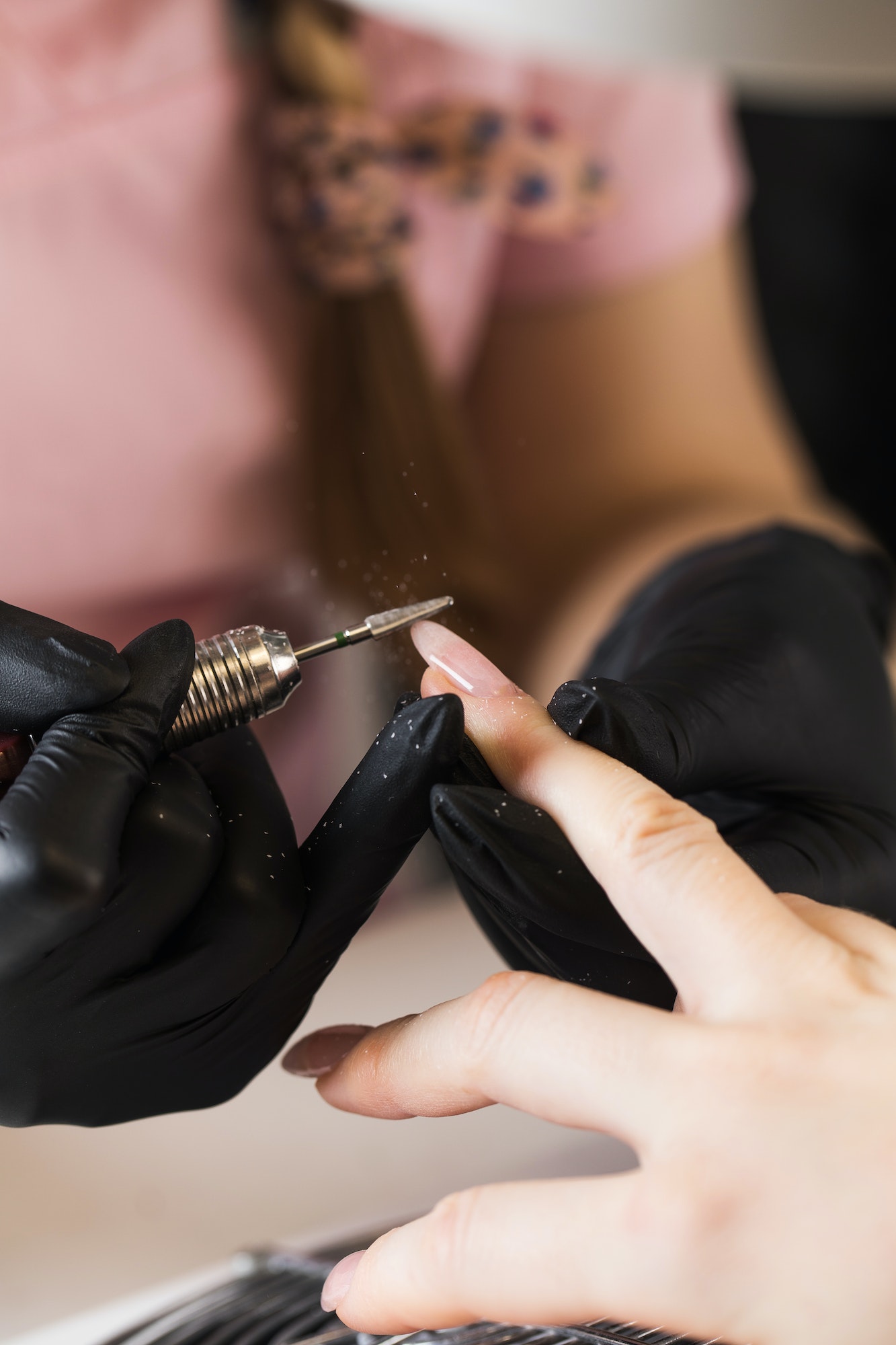 A manicurist removes gel polish from nails using a milling cutter. Hardware manicure close-up.